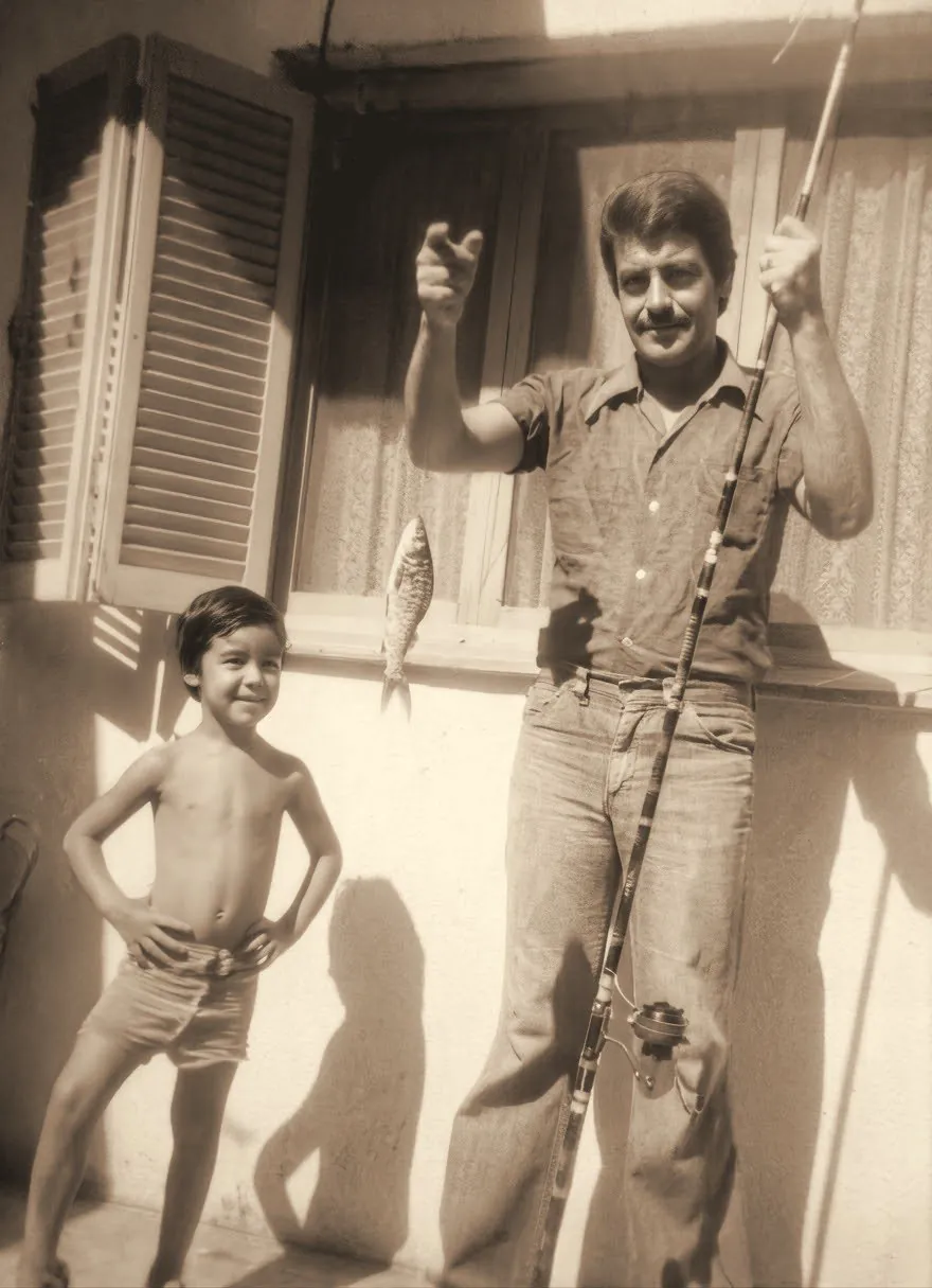 Foto antigua: un papá sostiene su caña de pescar y el pescado del día, junto a su hijo pequeño