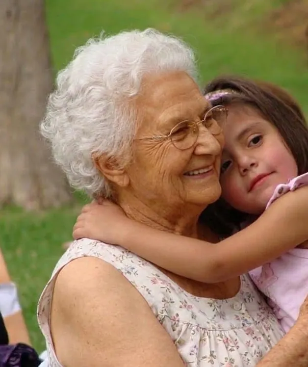 Una abuela sonríe mientras su nieta la abraza en un día de campo